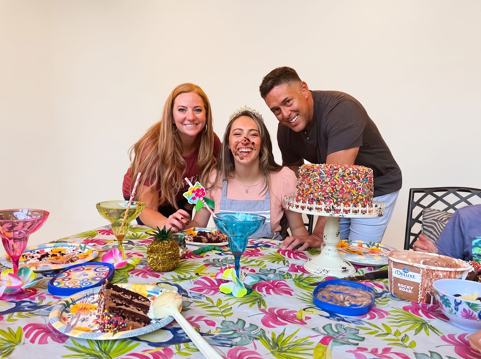 A family smiling around a birthday cake at a Paint Fusion style party