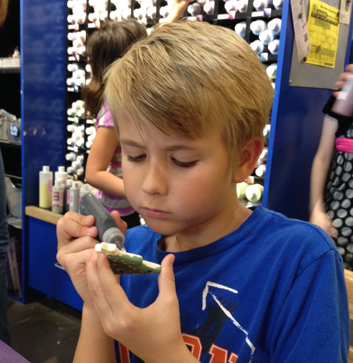 A boy painting a ceramic dinosaur at the Park City pottery studio