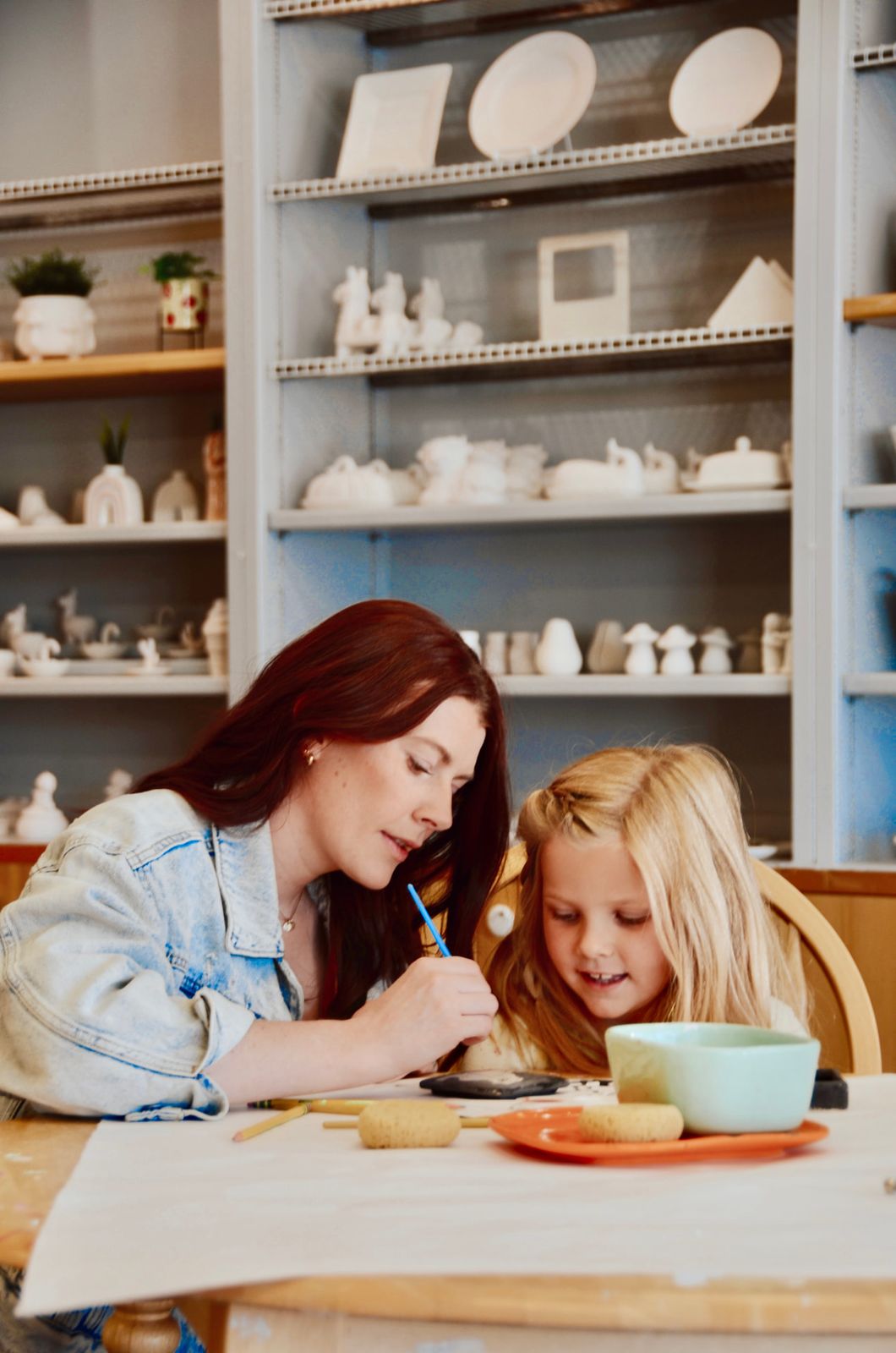A family painting pottery indoors at Paint Fusion Park City