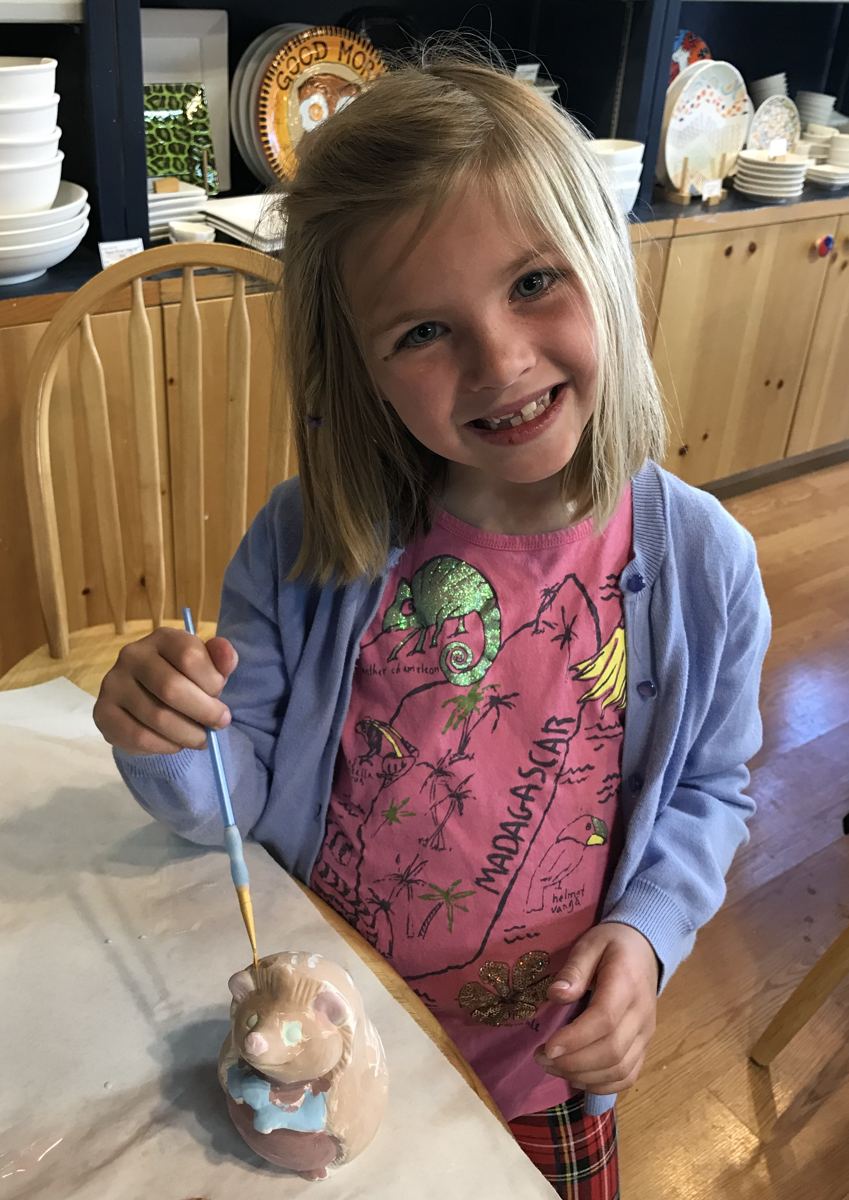 A child painting a ceramic figurine at Paint Fusion Park City