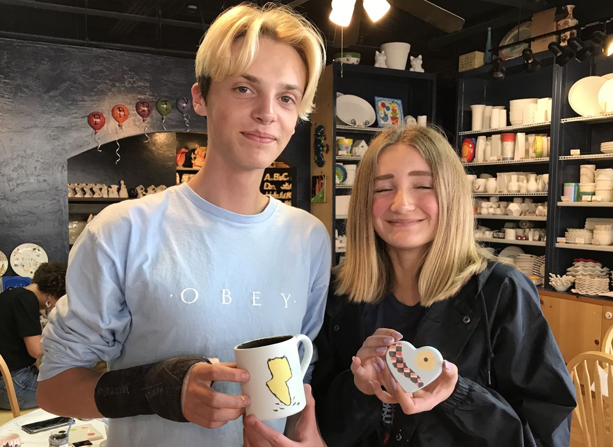 Friends showing off mugs they painted at a studio event in Park City